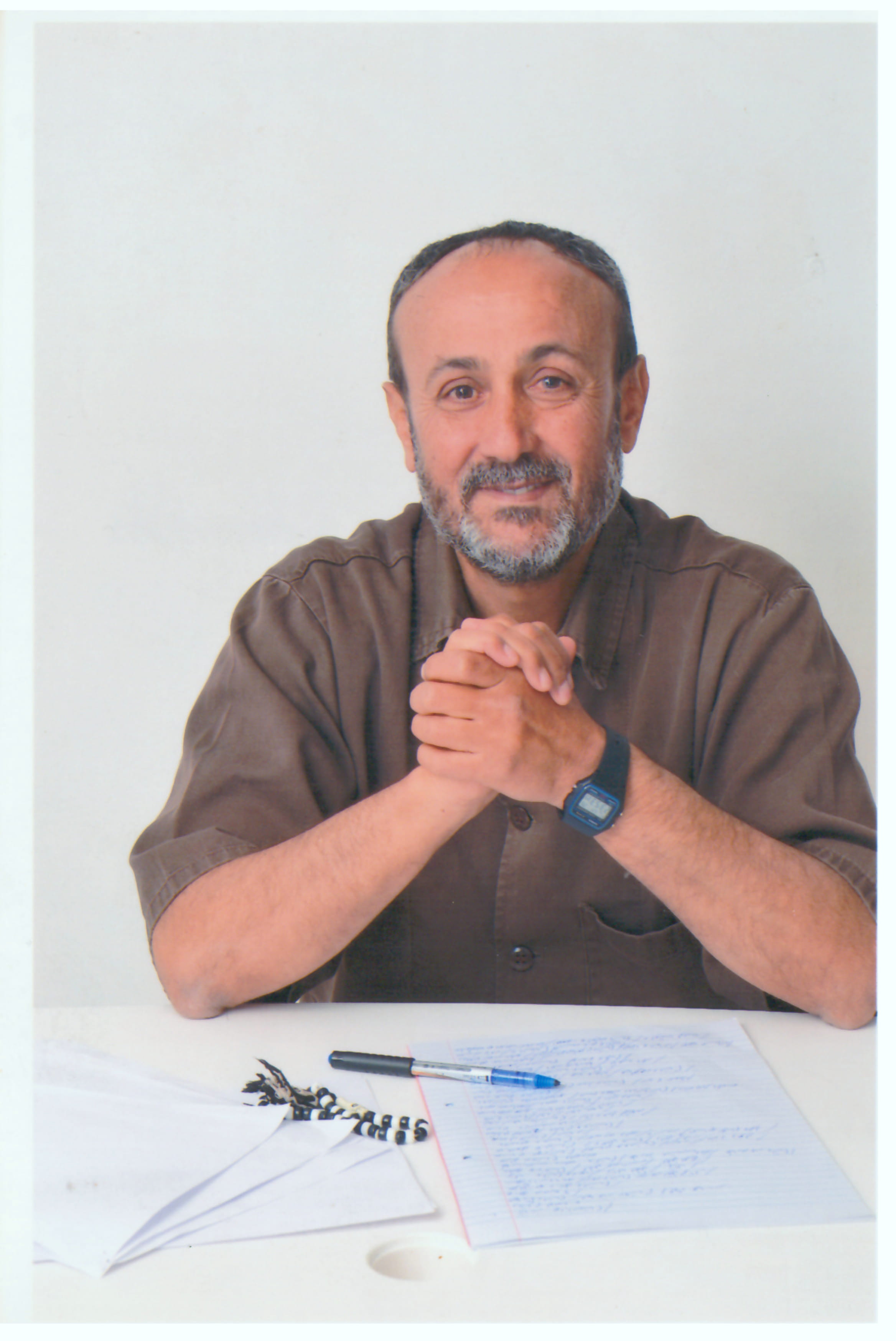 Foto do l&iacute;der palestino Marwan Image, um homem de cabelo curto, barba grisalha, vestindo uma camisa marrom e um rel&oacute;gio. 